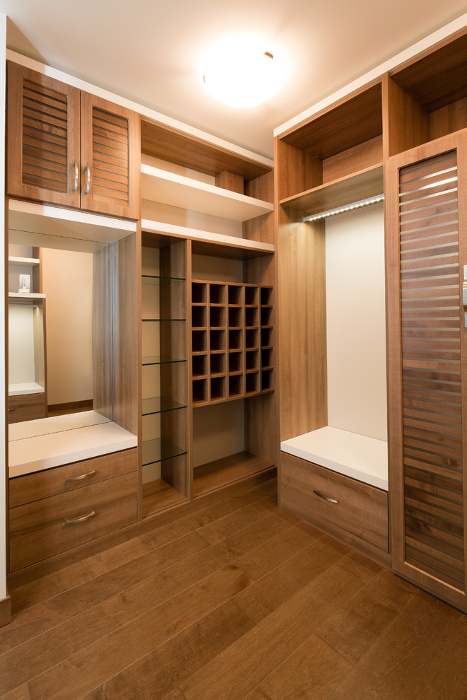 Imagen de armario vestidor moderno con puertas de armario de madera en tonos medios y suelo de madera oscura