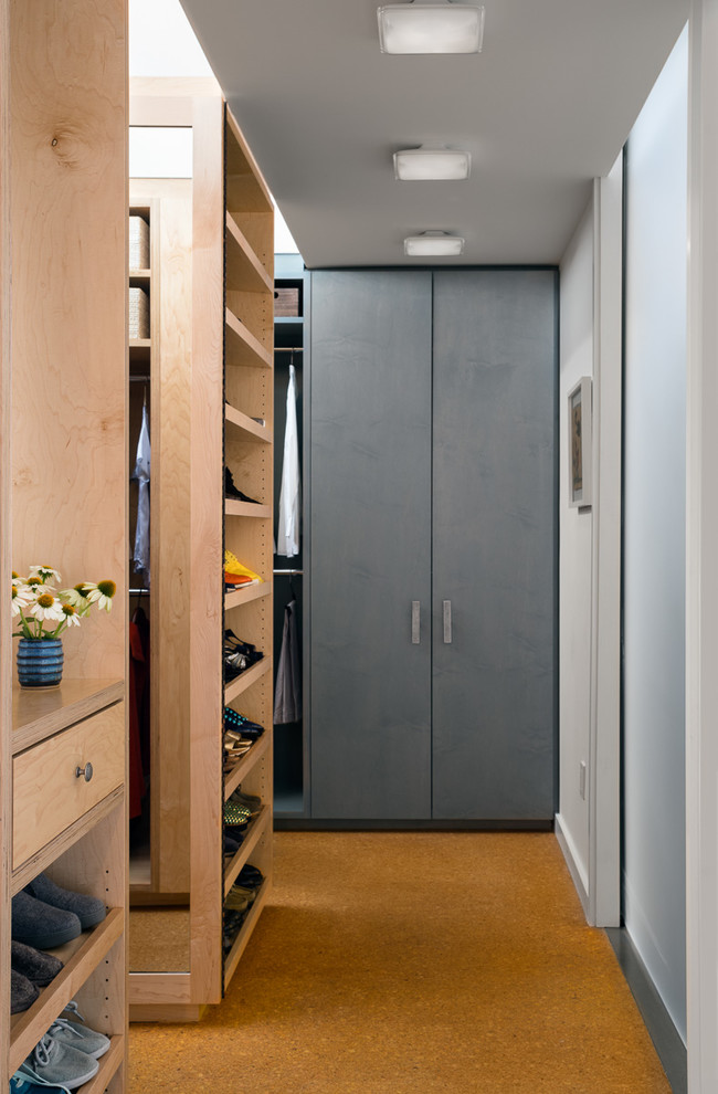 Diseño de armario vestidor unisex industrial grande con armarios abiertos, puertas de armario de madera clara, suelo de corcho y suelo marrón