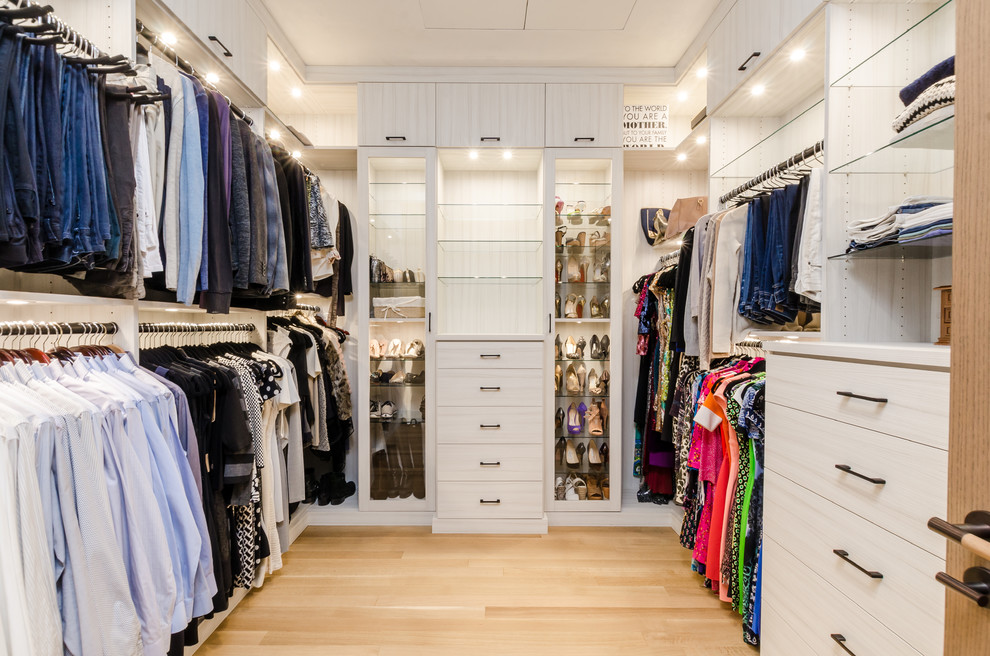 Ejemplo de armario vestidor unisex actual extra grande con suelo de madera clara y puertas de armario de madera clara