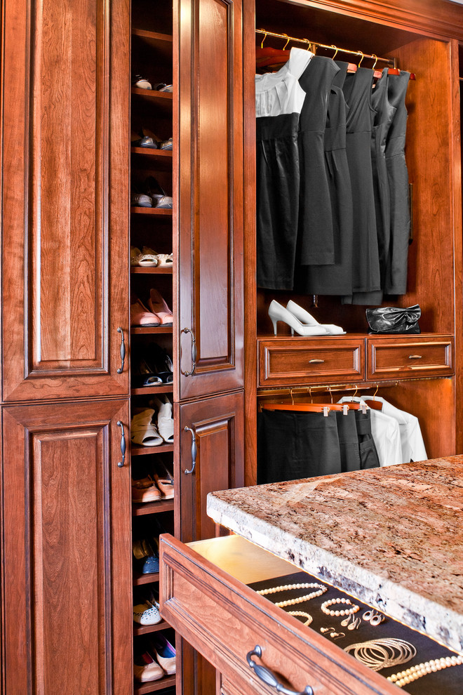 Example of a large classic women's medium tone wood floor walk-in closet design in Houston with raised-panel cabinets and medium tone wood cabinets