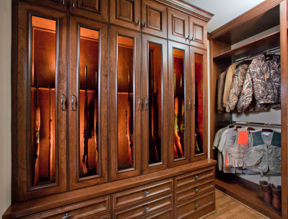 Modelo de vestidor de hombre tradicional grande con puertas de armario de madera oscura, suelo de madera en tonos medios y armarios con paneles empotrados