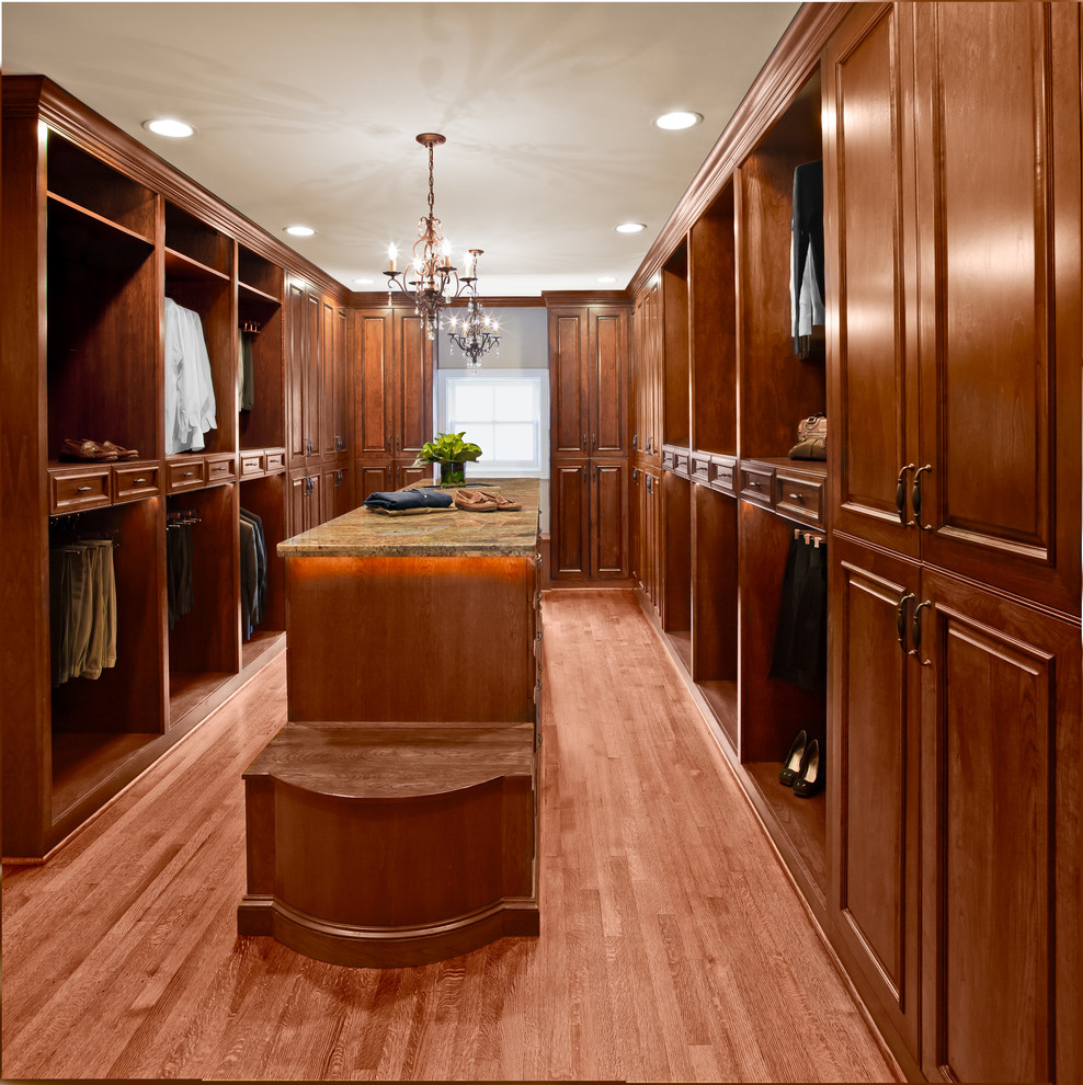 Modelo de armario vestidor unisex clásico grande con armarios con paneles con relieve, puertas de armario de madera en tonos medios y suelo de madera en tonos medios