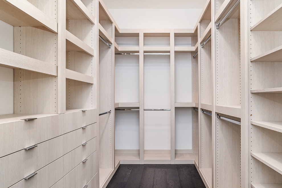 Imagen de armario vestidor de hombre actual grande con armarios con paneles con relieve, puertas de armario beige y suelo de madera oscura