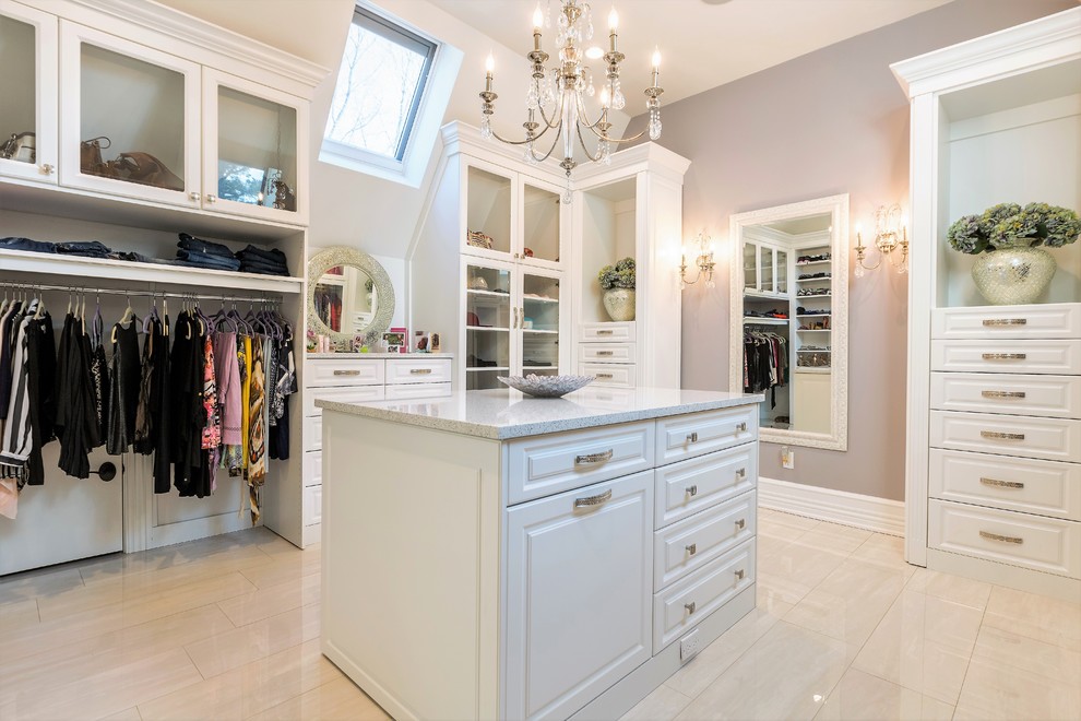 Example of a large transitional women's porcelain tile and beige floor walk-in closet design in New York with raised-panel cabinets and white cabinets