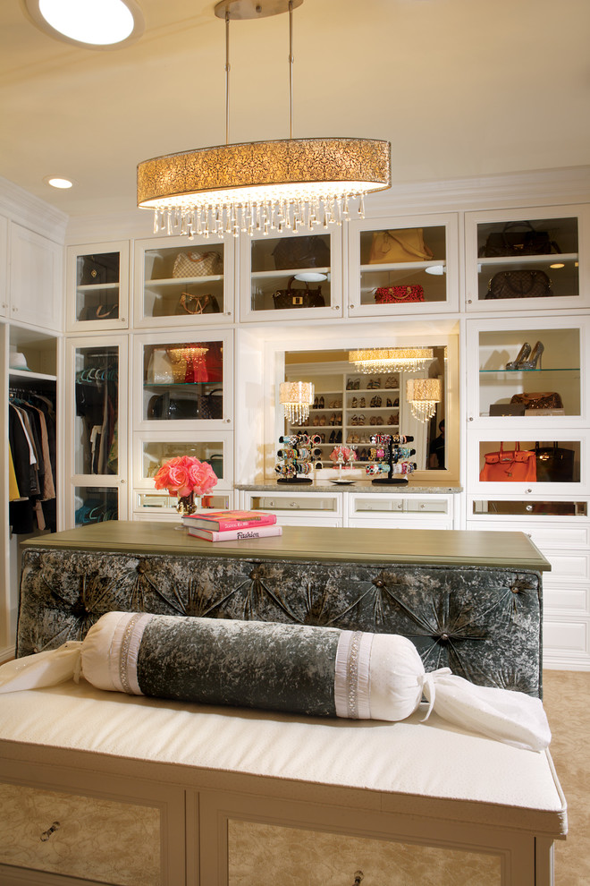 На фото: огромная гардеробная комната в стиле неоклассика (современная классика) с стеклянными фасадами, белыми фасадами и ковровым покрытием для женщин с