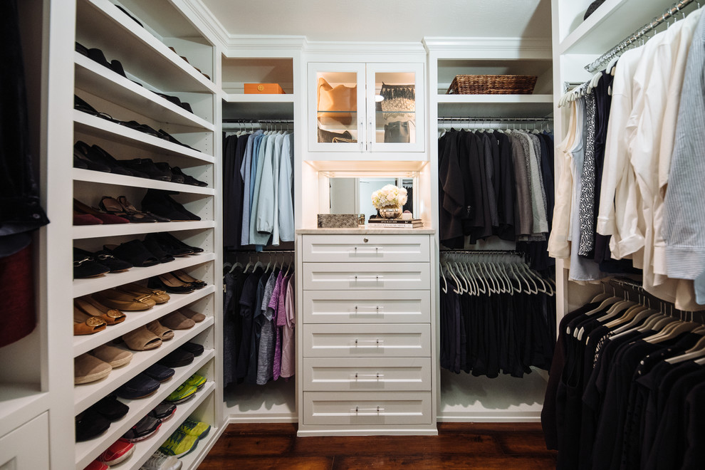 Diseño de armario vestidor de mujer clásico renovado pequeño con armarios con rebordes decorativos, puertas de armario blancas, suelo de madera oscura y suelo marrón