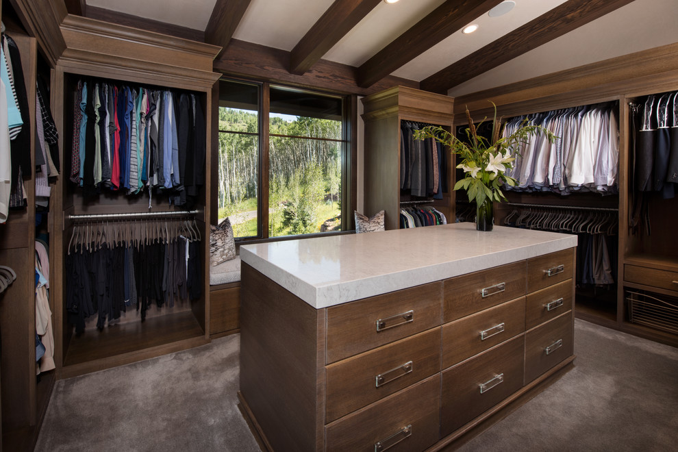 This is an example of a large traditional gender neutral walk-in wardrobe in Denver with flat-panel cabinets, medium wood cabinets and carpet.