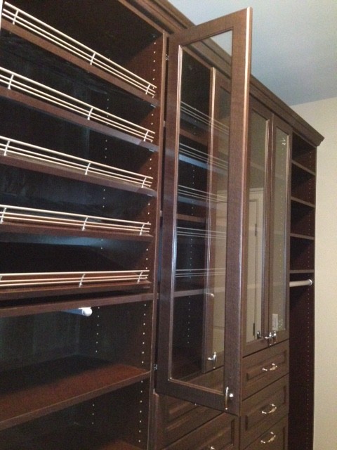 This is an example of a large classic walk-in wardrobe for men in Other with raised-panel cabinets, dark wood cabinets and medium hardwood flooring.