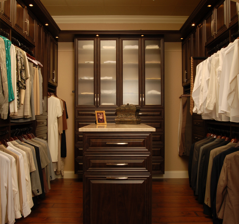 Modelo de armario vestidor unisex clásico de tamaño medio con armarios con paneles con relieve, puertas de armario de madera en tonos medios y suelo de madera oscura