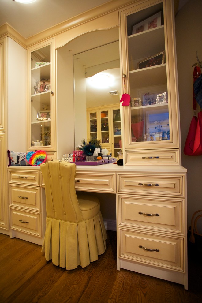 Cette photo montre un dressing room chic de taille moyenne pour une femme avec un placard avec porte à panneau surélevé, des portes de placard blanches, un sol en bois brun et un sol marron.