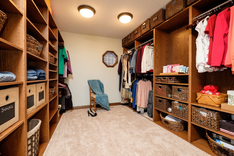 На фото: гардеробная комната среднего размера, унисекс в стиле кантри с открытыми фасадами, темными деревянными фасадами и ковровым покрытием с