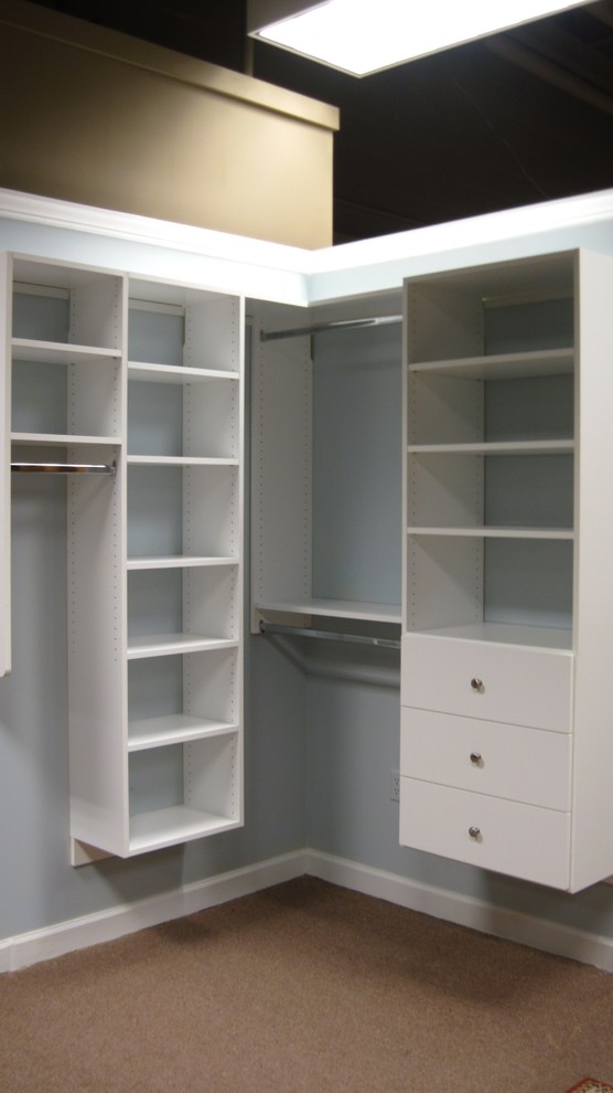 Ejemplo de armario vestidor unisex clásico renovado grande con armarios con paneles con relieve, puertas de armario grises y suelo de madera clara