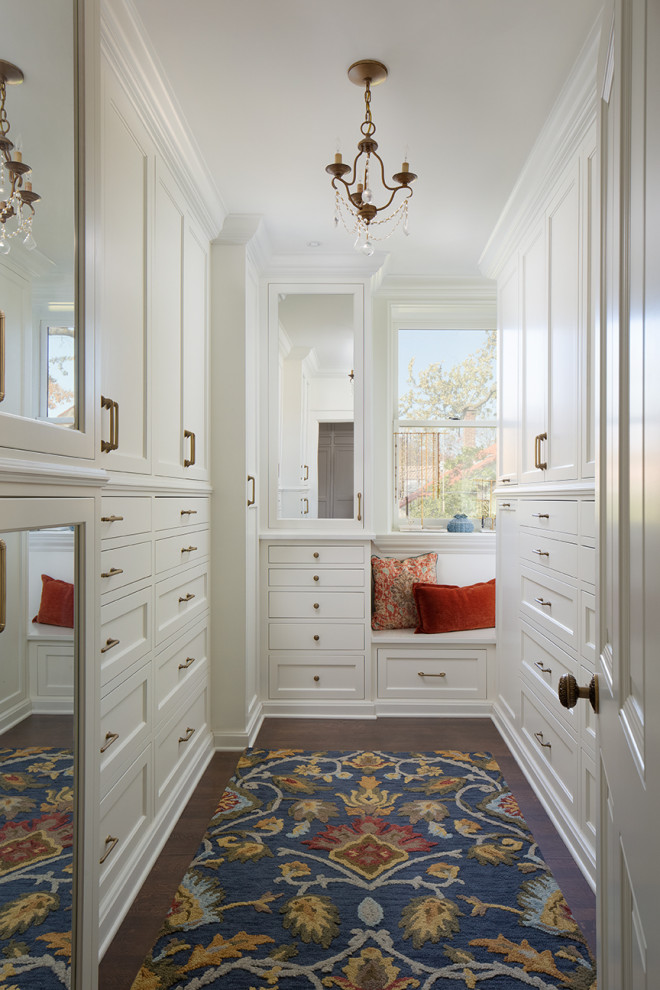 Стильный дизайн: гардеробная комната унисекс в классическом стиле с белыми фасадами, темным паркетным полом и коричневым полом - последний тренд