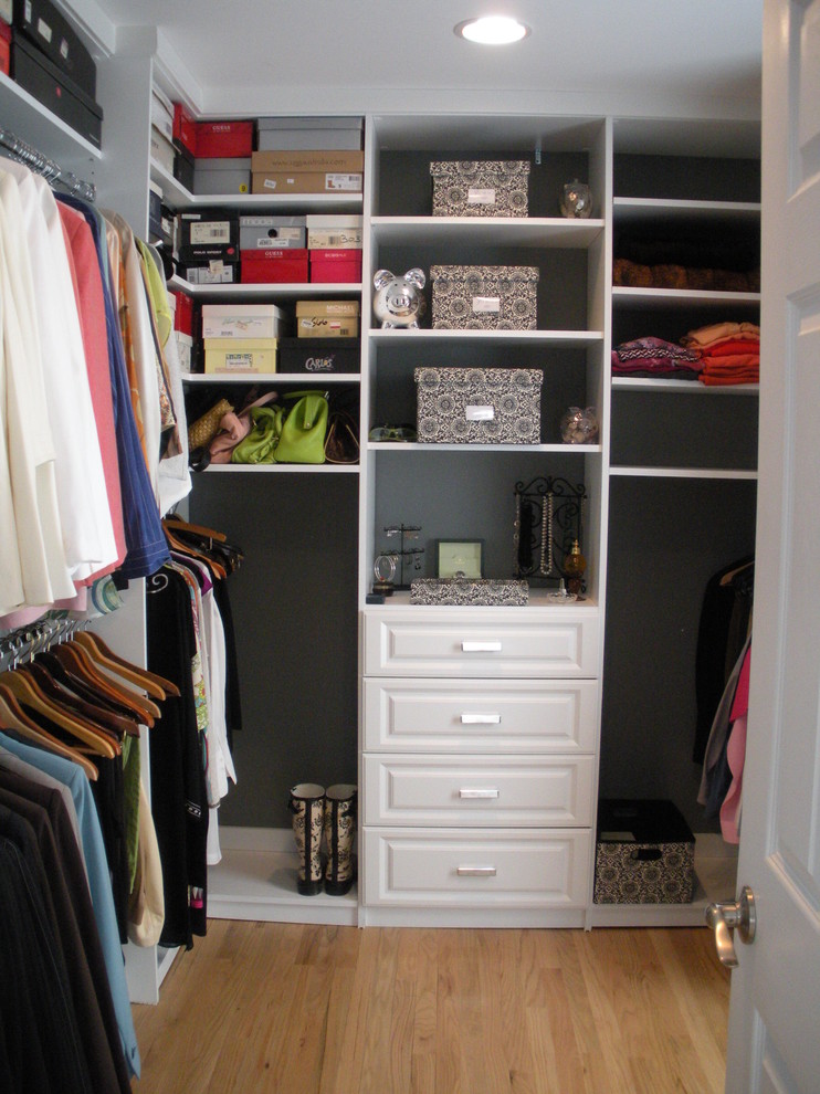 Imagen de armario vestidor de mujer clásico de tamaño medio con armarios con paneles con relieve, puertas de armario blancas y suelo de madera clara