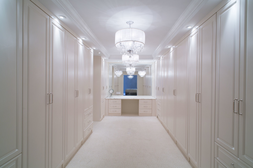 Стильный дизайн: большая гардеробная комната унисекс в стиле неоклассика (современная классика) с фасадами с выступающей филенкой, белыми фасадами и ковровым покрытием - последний тренд