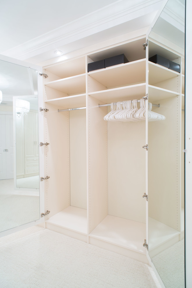 Ejemplo de armario vestidor unisex tradicional renovado grande con armarios con paneles con relieve, puertas de armario blancas y moqueta