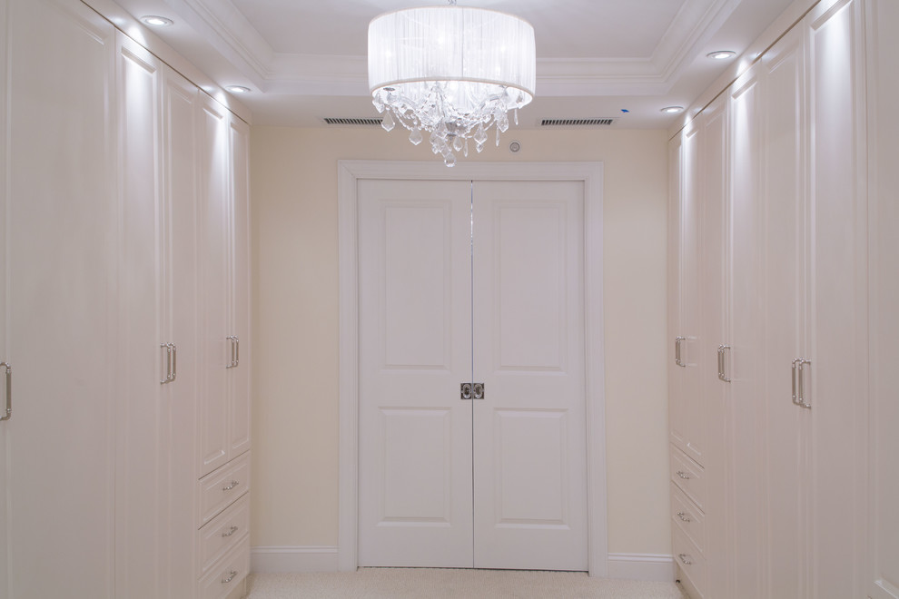 Идея дизайна: большая гардеробная комната унисекс в стиле неоклассика (современная классика) с фасадами с выступающей филенкой, белыми фасадами и ковровым покрытием
