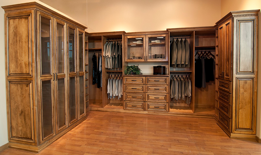 Inspiration for a large timeless men's dark wood floor and brown floor walk-in closet remodel in Denver with raised-panel cabinets and dark wood cabinets