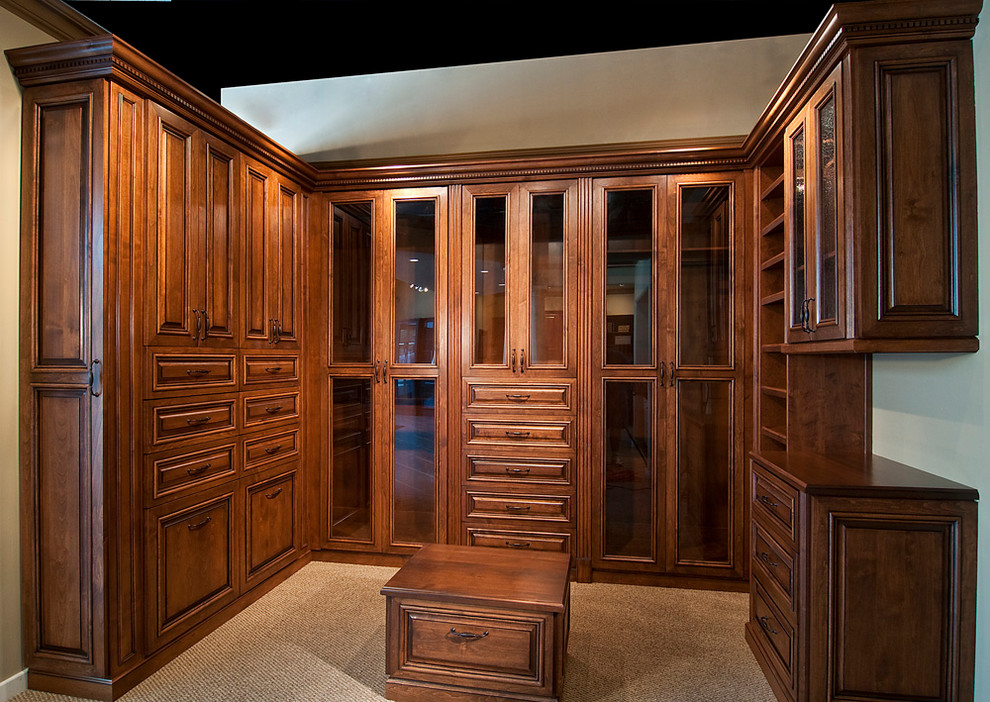 На фото: большая гардеробная комната унисекс в классическом стиле с фасадами с выступающей филенкой, темными деревянными фасадами, ковровым покрытием и коричневым полом