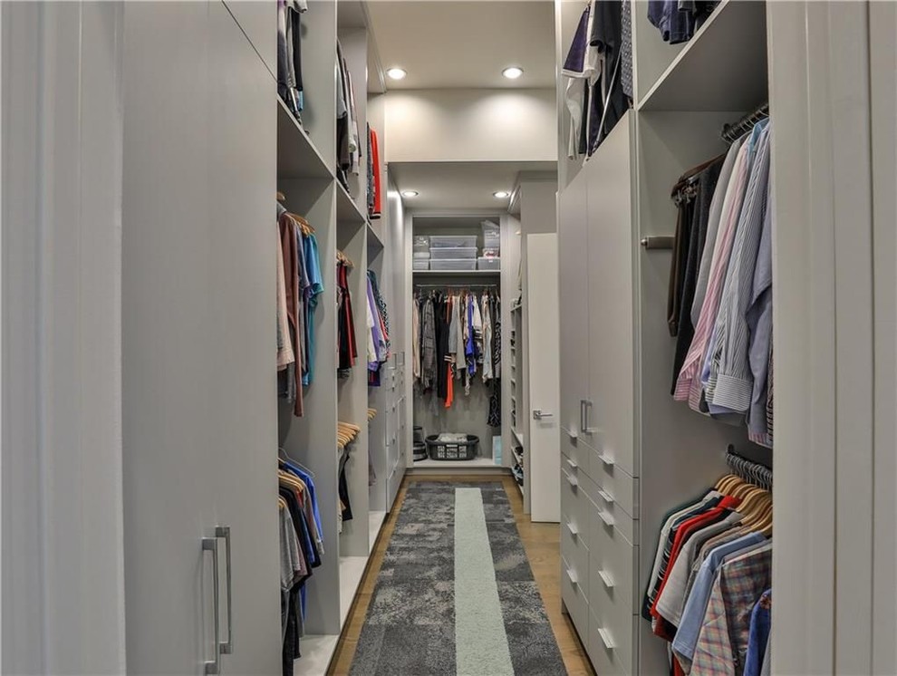 Medium sized contemporary gender neutral walk-in wardrobe in Dallas with flat-panel cabinets, white cabinets, light hardwood flooring and brown floors.