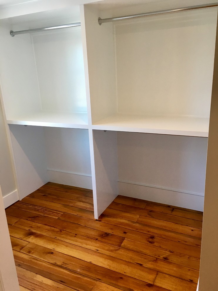 Diseño de armario vestidor clásico pequeño con armarios con paneles empotrados, puertas de armario blancas y suelo de madera en tonos medios