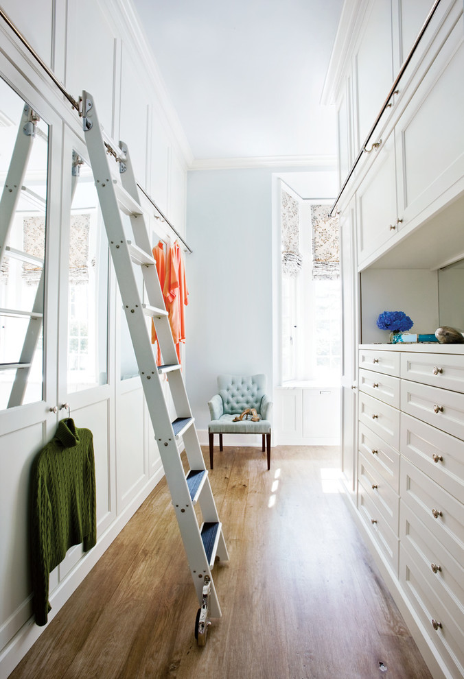 Foto de armario y vestidor clásico con puertas de armario blancas y suelo de madera clara