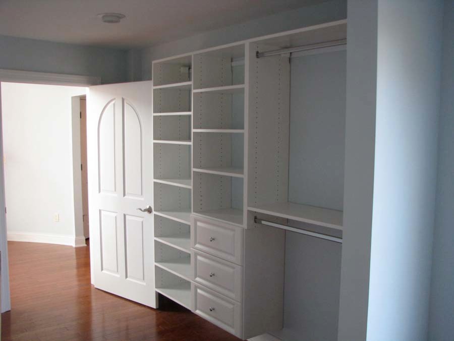 Modelo de armario unisex clásico de tamaño medio con puertas de armario blancas y suelo de madera en tonos medios