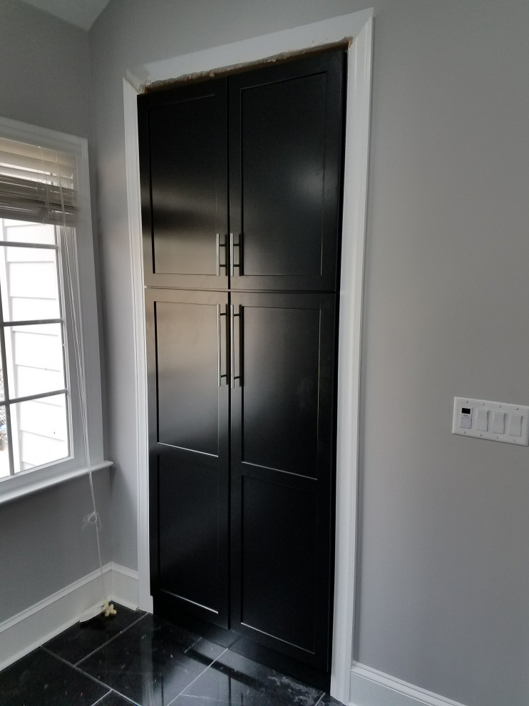 Ejemplo de armario vestidor unisex minimalista grande con puertas de armario negras, suelo de mármol y suelo negro
