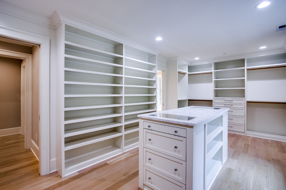 Design ideas for a large traditional gender neutral walk-in wardrobe in DC Metro with recessed-panel cabinets, white cabinets, light hardwood flooring and brown floors.