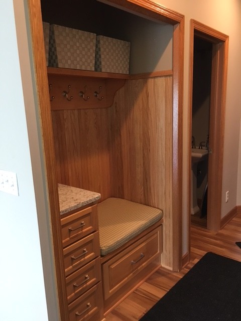Modelo de armario tradicional renovado con armarios con paneles empotrados, puertas de armario de madera clara, suelo laminado y suelo marrón