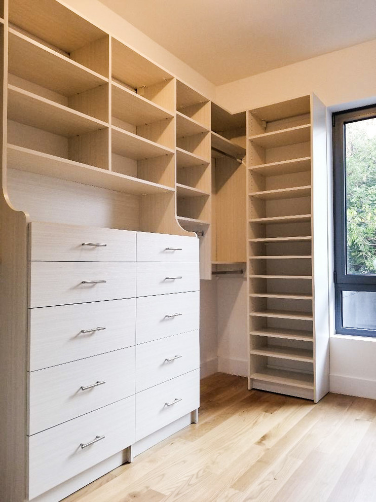 Cette image montre un dressing minimaliste en bois clair de taille moyenne avec un placard à porte plane et parquet clair.