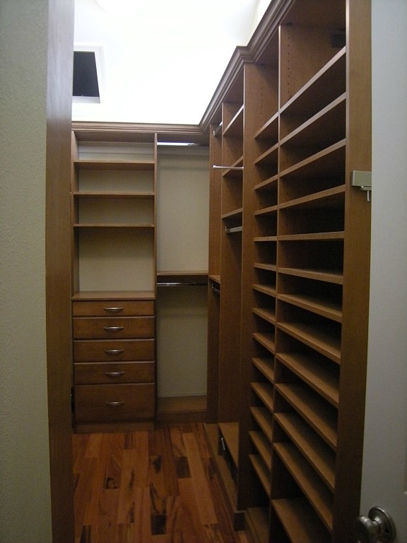 Foto de armario vestidor unisex clásico grande con armarios abiertos, puertas de armario de madera en tonos medios, suelo de madera oscura y suelo marrón