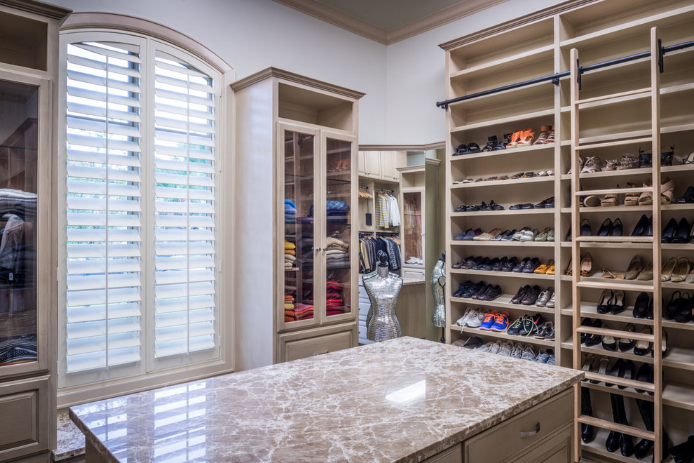 Design ideas for an expansive traditional gender neutral walk-in wardrobe in Houston with raised-panel cabinets, beige cabinets and carpet.