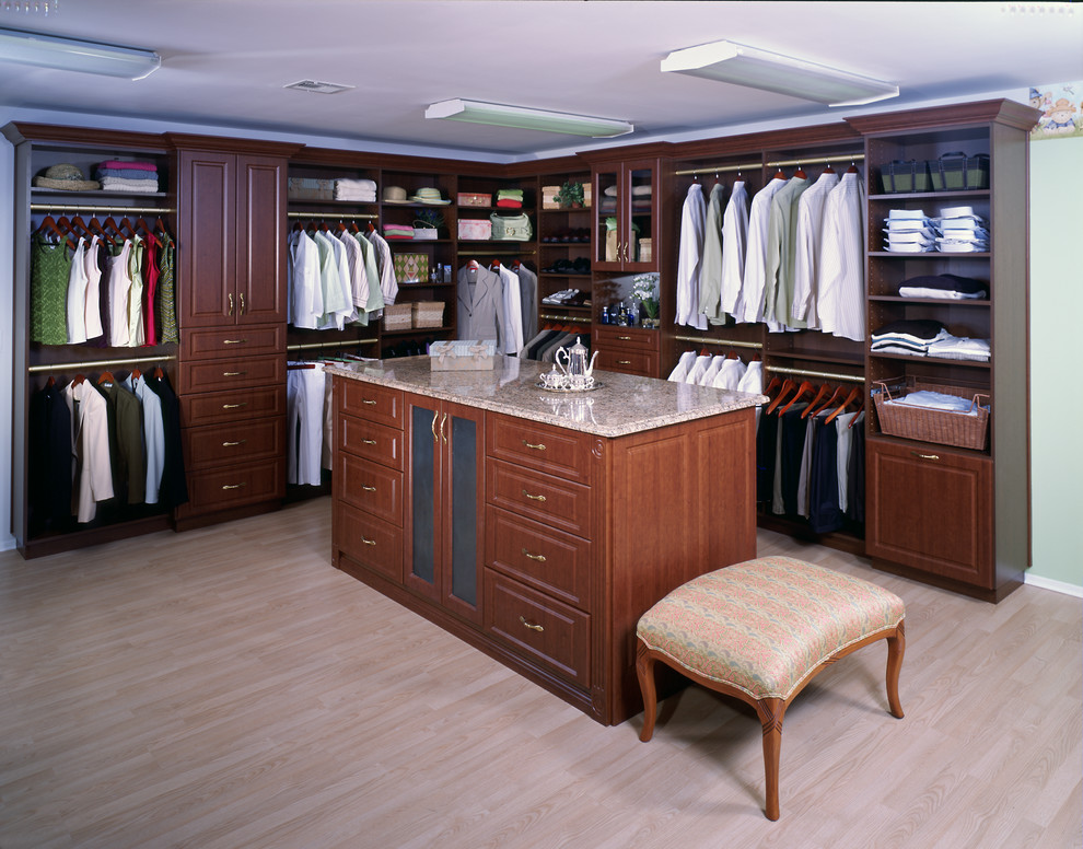 Imagen de armario vestidor unisex tradicional grande con armarios con paneles con relieve, puertas de armario de madera en tonos medios, suelo de madera clara y suelo beige