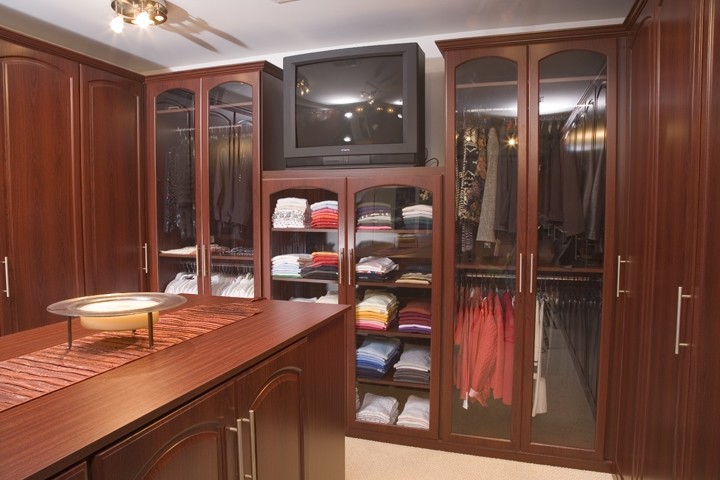 Ejemplo de armario vestidor unisex tradicional grande con armarios con paneles con relieve, puertas de armario de madera en tonos medios y moqueta
