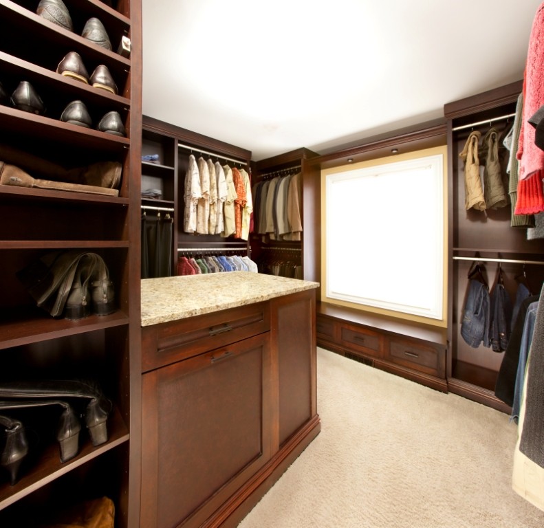 Modelo de armario vestidor unisex de estilo americano grande con armarios estilo shaker, puertas de armario de madera en tonos medios, moqueta y suelo beige
