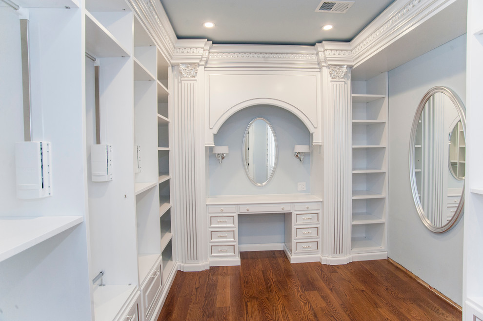 Inspiration for a large mediterranean women's walk-in wardrobe in DC Metro with glass-front cabinets, white cabinets and medium hardwood floors.