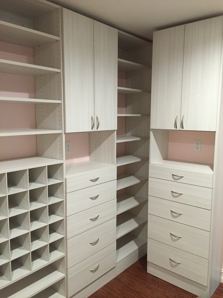 Ejemplo de armario vestidor de mujer minimalista de tamaño medio con armarios con paneles lisos, suelo de madera en tonos medios y puertas de armario de madera clara