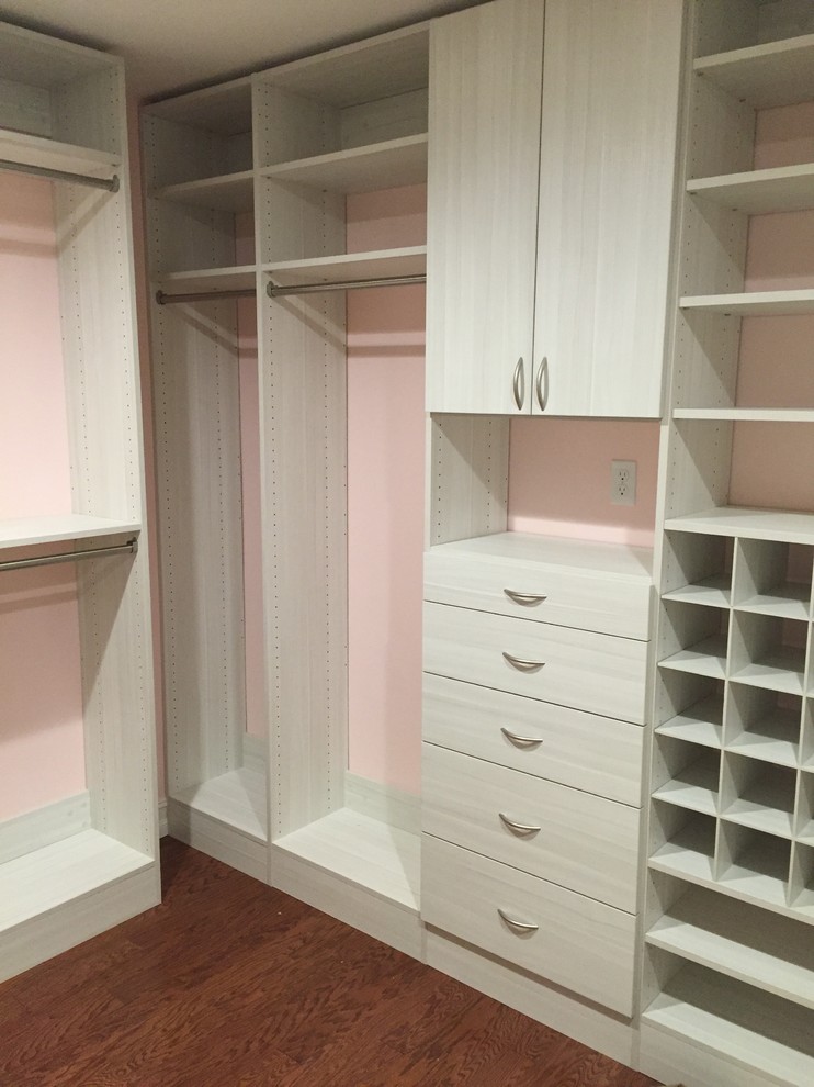 Medium sized modern walk-in wardrobe for women in Miami with flat-panel cabinets, light wood cabinets and medium hardwood flooring.