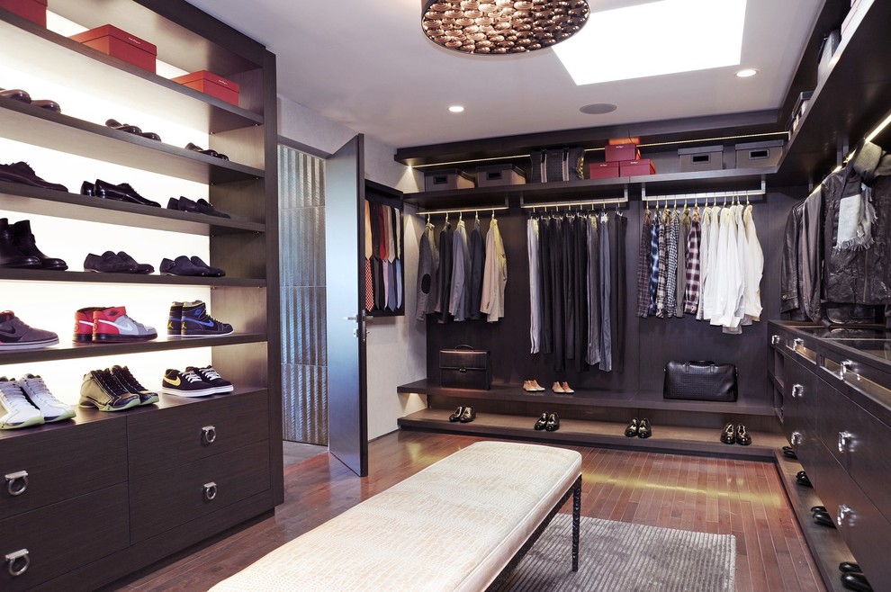 Modernes Ankleidezimmer mit Ankleidebereich, offenen Schränken, dunklen Holzschränken und braunem Holzboden in Miami