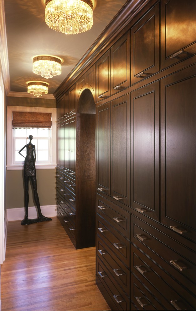 Foto de armario vestidor unisex tradicional renovado grande con puertas de armario de madera en tonos medios, suelo de madera en tonos medios y armarios con rebordes decorativos