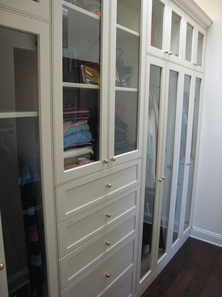 Modelo de armario vestidor tradicional renovado de tamaño medio con armarios tipo vitrina, puertas de armario blancas, suelo de madera oscura y suelo marrón
