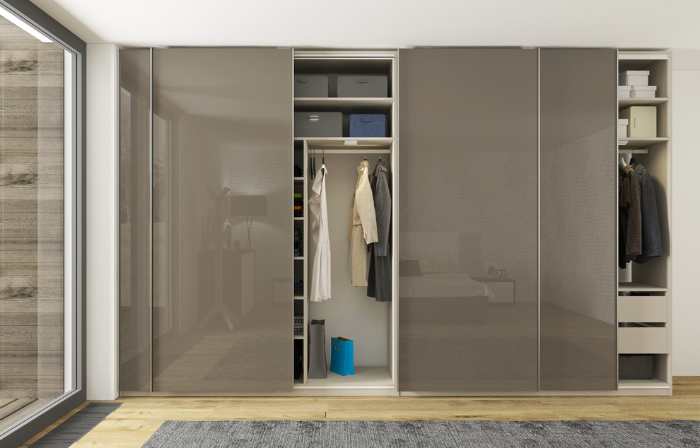Immagine di un armadio o armadio a muro unisex minimalista di medie dimensioni con ante lisce, parquet chiaro e ante grigie