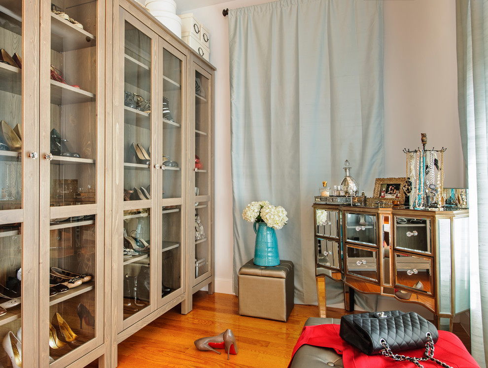 Inredning av ett klassiskt mellanstort walk-in-closet för kvinnor, med luckor med glaspanel, skåp i ljust trä, mellanmörkt trägolv och brunt golv