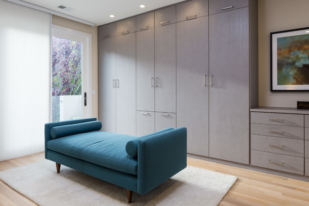 Aménagement d'un dressing room moderne neutre avec un placard à porte plane, parquet clair et des portes de placard grises.