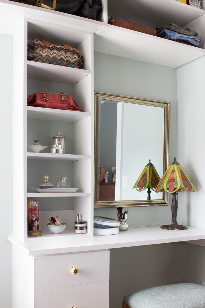 Medium sized classic dressing room for women in New York with flat-panel cabinets, white cabinets and light hardwood flooring.