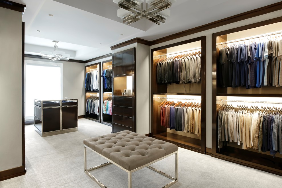 Aménagement d'un dressing room contemporain en bois foncé pour un homme avec un placard sans porte, moquette et un sol beige.