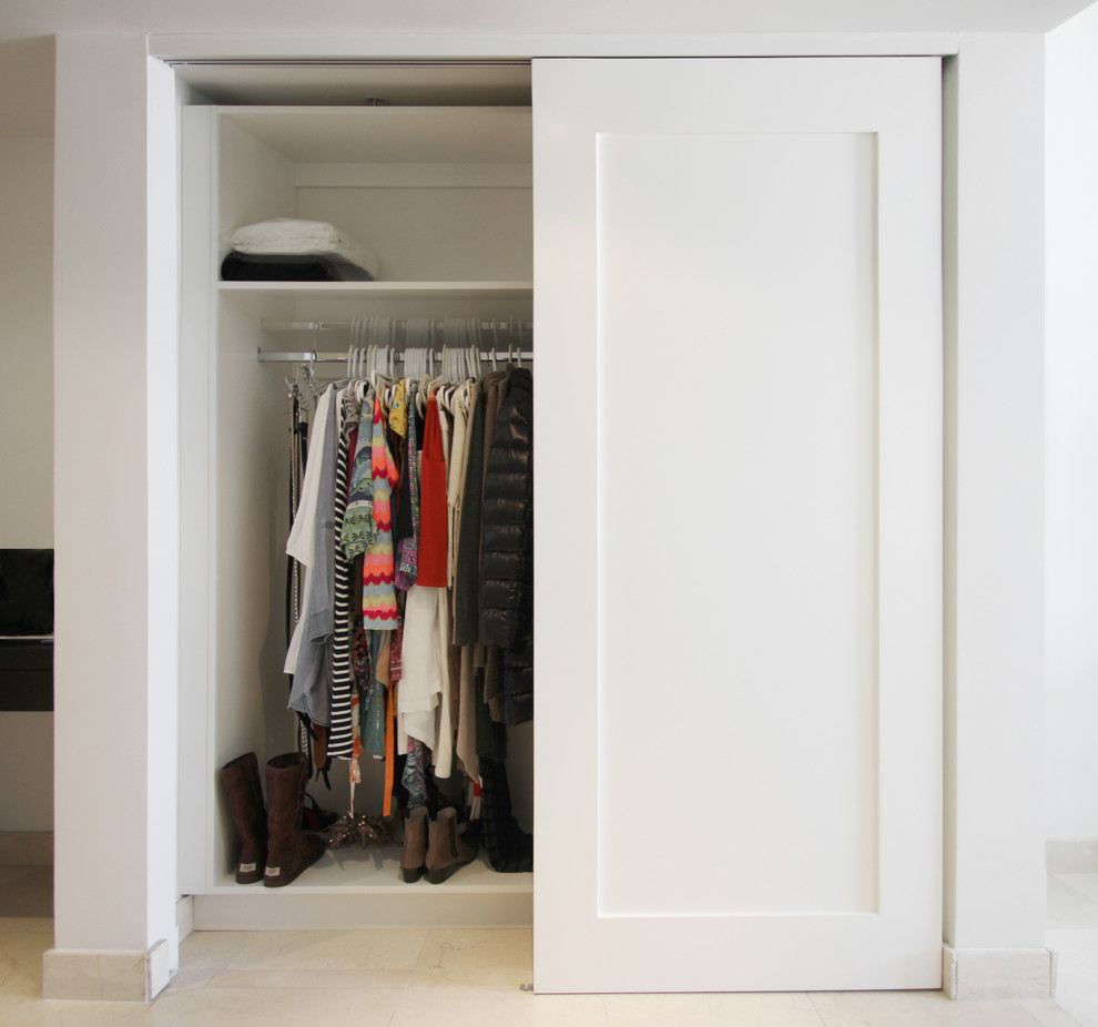 Ejemplo de armario unisex actual pequeño con armarios con paneles lisos, puertas de armario blancas, suelo de baldosas de porcelana y suelo beige