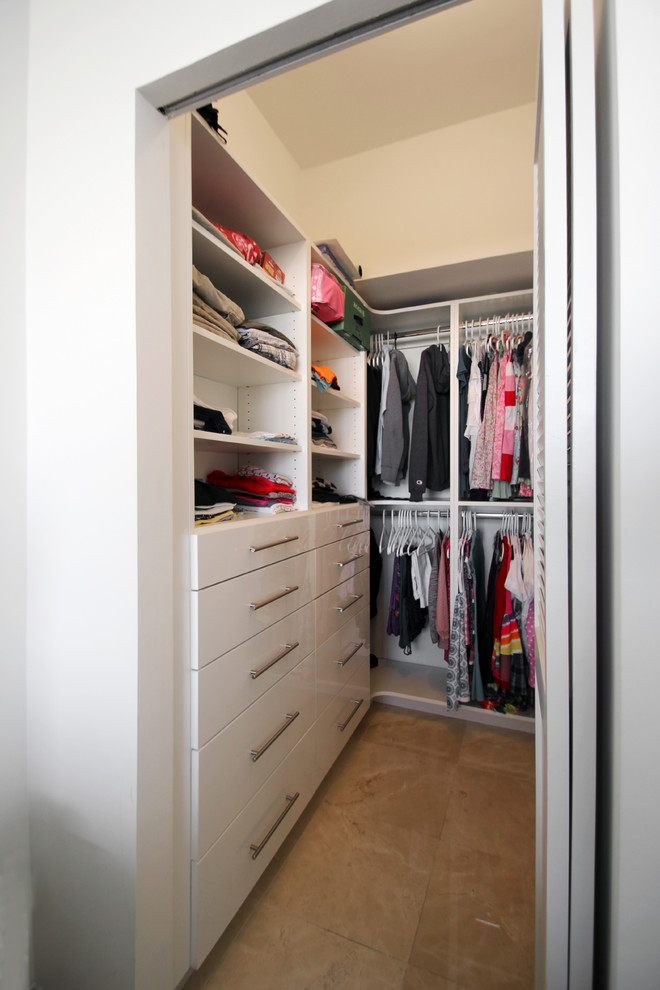 Modern inredning av ett litet walk-in-closet för könsneutrala, med släta luckor, vita skåp, klinkergolv i porslin och beiget golv