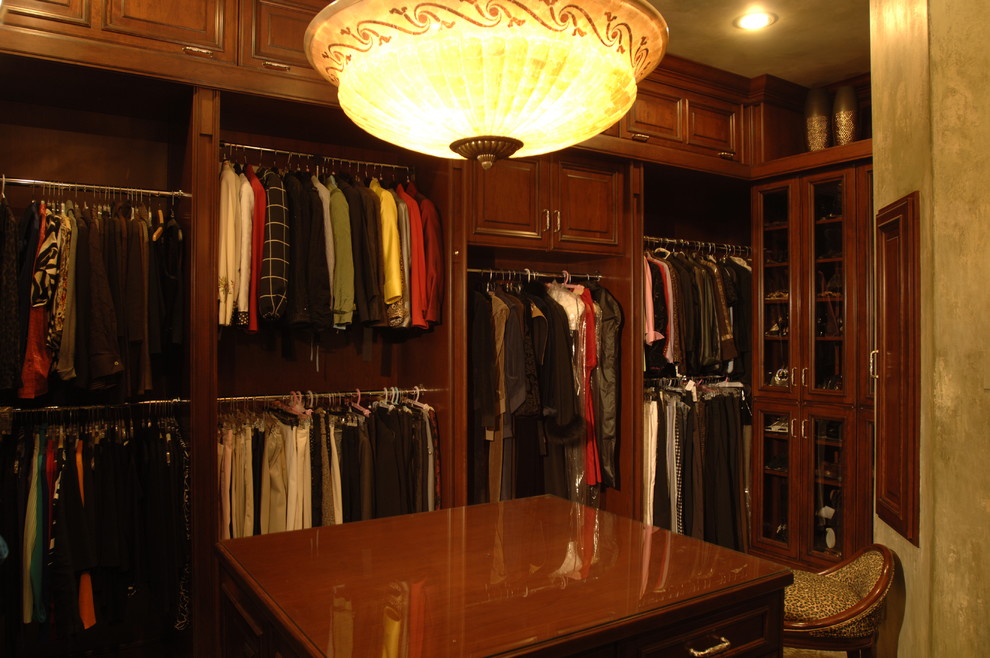 Стильный дизайн: большая гардеробная комната унисекс в классическом стиле с темными деревянными фасадами - последний тренд